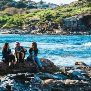 Three women sitting on rocks near river