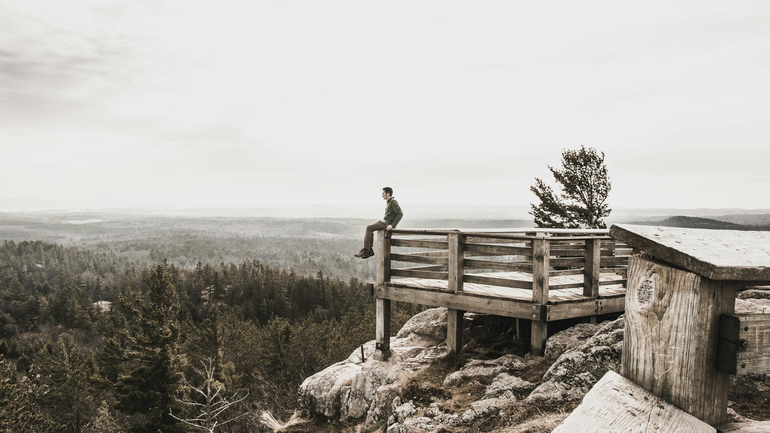 Man sitting on deck overlooking mountain