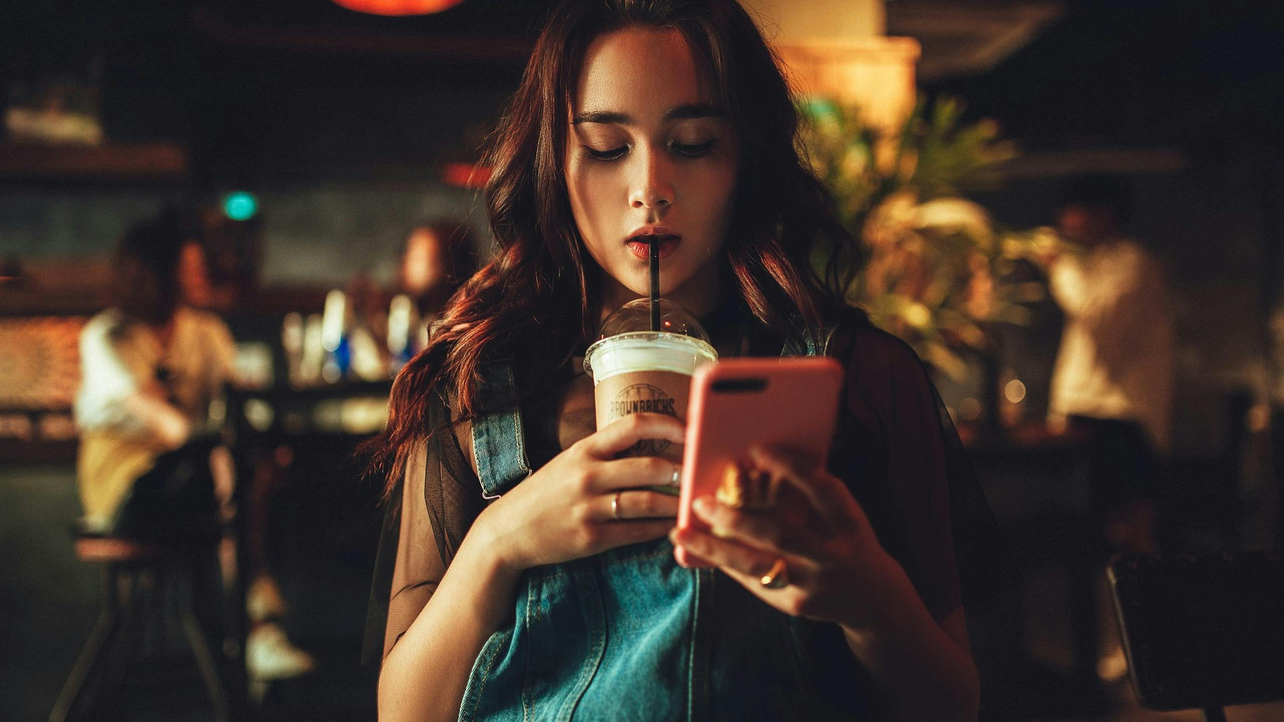 Woman staring at phone while drinking coffee