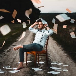 Man sitting with books flying around him